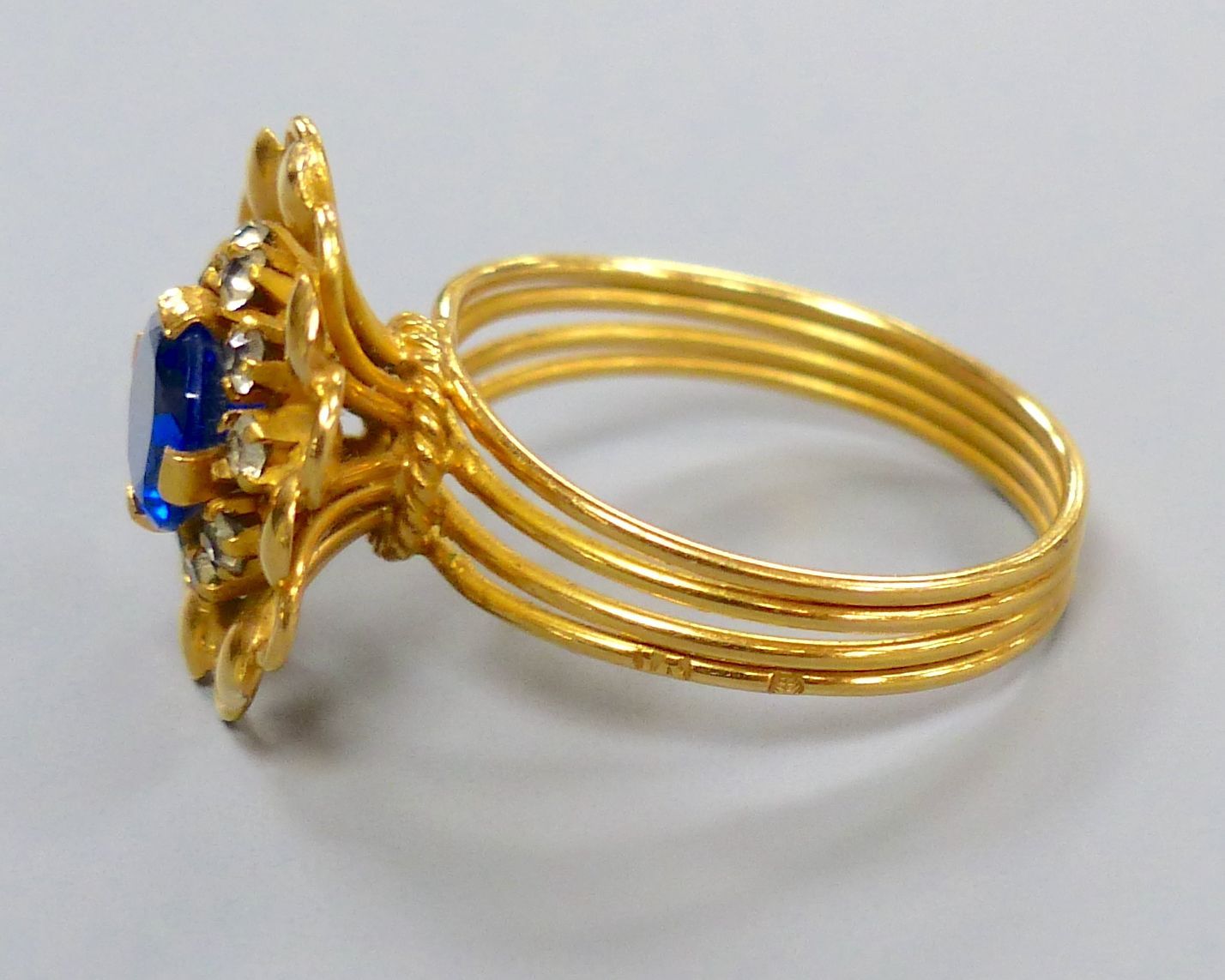 A Middle Eastern yellow metal ring, set with a blue and white paste stones, size O/P, gross 4.8 grams.